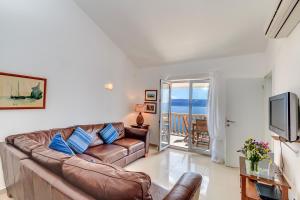 a living room with a leather couch and a television at Villa Katarina in Stanići