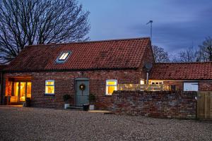 una casa de ladrillo con techo rojo en The Bolthole barn with wood-fired hot tub en Glentworth