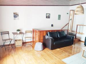 uma sala de estar com um sofá de couro preto e uma mesa em Casa d'Avó na Carrapateira