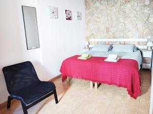 a bedroom with a bed with a red blanket and a chair at Casa d'Avó in Carrapateira