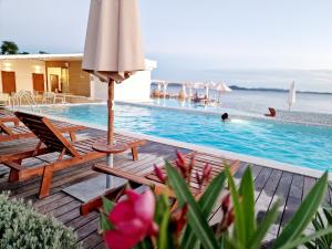 una piscina con sillas, una sombrilla y una piscina en Residence-Apartment-Giuliano-Punta Skala, en Petrcane