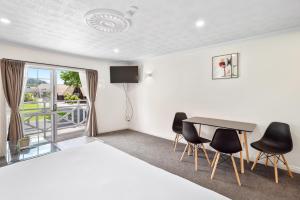 Habitación con cama, mesa y sillas. en Ashleigh Court Motel, en Rotorua