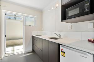 een witte keuken met een wastafel en een magnetron bij Ashleigh Court Motel in Rotorua