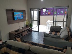 a living room with two couches and a flat screen tv at Apt. Enseada Guarujá in Guarujá