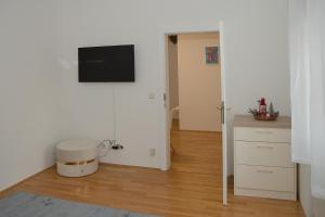 a living room with a television on a white wall at Blue Lotus Apartment in Vienna