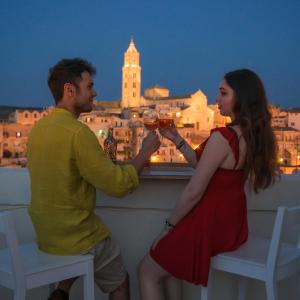 un uomo e una donna che bevono vino sul balcone di The View Matera a Matera