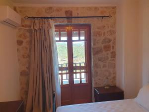 a bedroom with a bed and a door with a window at Nireas : Stone Villa in Zakynthos
