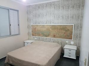 a bedroom with a bed and a painting on the wall at Apt. Enseada Guarujá in Guarujá