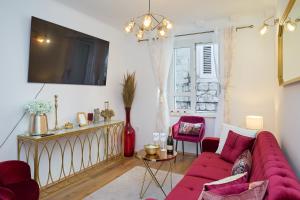 a living room with a red couch and a tv at Old Town Casa Nevia- Deluxe Holiday Home in Dubrovnik with Stunning Views in Dubrovnik