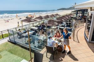 um grupo de pessoas sentadas em mesas na praia em sunrise on the beach em Gold Coast