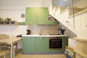 una cocina con armarios verdes y fregadero en La brezza del lago, en Marone