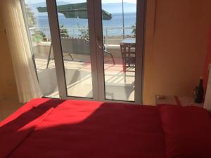 um quarto com uma cama vermelha e vista para uma varanda em DREAM APARTMENT Vlore em Vlorë