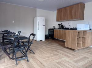 a kitchen with a refrigerator and a table and chairs at Pousada Aconchego in Ametista do Sul
