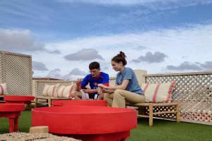 dos personas sentadas en un patio jugando con sus teléfonos en Miostello Lifestyle Hostel Marrakech, en Marrakech