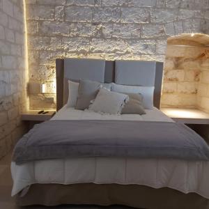um quarto com uma cama branca e uma parede de pedra em Palazzo Momi em Bari