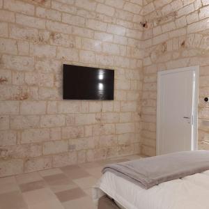 1 dormitorio con pared de piedra y TV de pantalla plana en Palazzo Momi en Bari