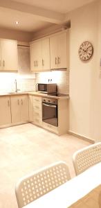 a kitchen with white cabinets and a clock on the wall at Modern home, 6' from the Metro in Athens