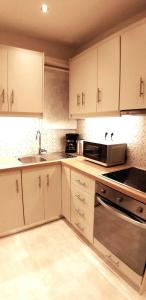 a kitchen with white cabinets and a sink and a microwave at Modern home, 6' from the Metro in Athens