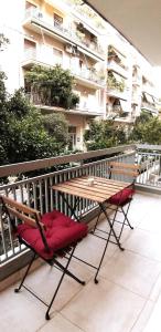 a wooden table and a red chair on a balcony at Modern home, 6' from the Metro in Athens