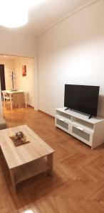 a living room with a flat screen tv and a table at Modern home, 6' from the Metro in Athens
