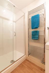 a bathroom with a glass shower stall and blue towels at Broads Reach - Norfolk Holiday Properties in Stalham