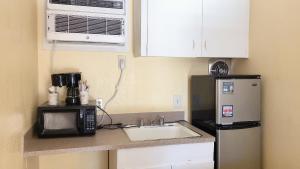 a kitchen with a sink and a microwave and a refrigerator at Royal Palace Inn and Suites Myrtle Beach Ocean Blvd in Myrtle Beach