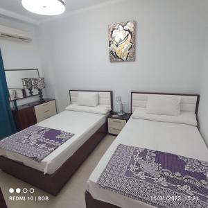 een slaapkamer met twee bedden en een schilderij aan de muur bij Apartment at ElKarma Aqua beach Resort in Hurghada +33 foto's