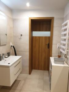 Łazienka z umywalką i drewnianymi drzwiami w obiekcie Apartament pod Grojcem w Żywcu