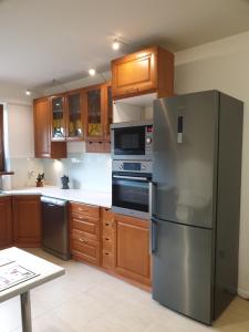 a kitchen with a stainless steel refrigerator and wooden cabinets at Apartament pod Grojcem in Żywiec