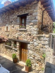 une maison en pierre avec une fenêtre et des plantes devant dans l'établissement Elpajardeportilla, à León