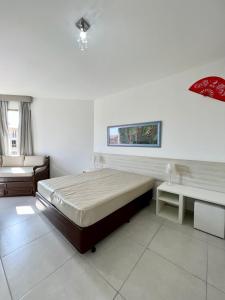 een witte slaapkamer met een bed en een bank bij Loft Sahy - Condado Aldeia dos Reis in Mangaratiba