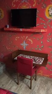 TV en una pared roja con silla y mesa en Catania Sicula Folk, en Catania