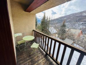 a balcony with a table and chairs and a view at Studio Montagne - Plein Soleil et Terrasse in Briançon