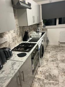 a kitchen with a stove and a washing machine at Accu care apartment in London