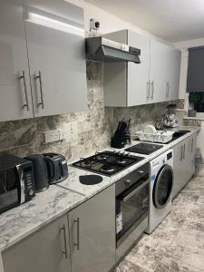 a kitchen with a stove and a washing machine at Accu care apartment in London