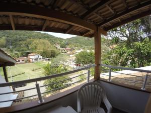 un balcón con una silla blanca y vistas a un campo en Pousada Bizkaia, en Florianópolis