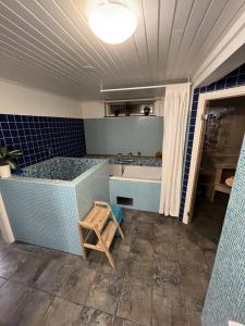 uma casa de banho com uma banheira, um lavatório e um banco em Villa Linneryd 1 em Linneryd