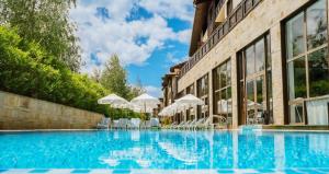 a swimming pool in front of a building with chairs and umbrellas at Apartaments by Zenit in Terra Complex B16 & C18 near Bansko in Razlog