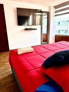 1 cama roja en una habitación con TV en la pared en Hermoso departamento con jacuzzi privado, en Quito
