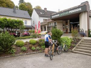 due persone in piedi con le loro biciclette davanti a un negozio di Gasthof Zur Traube a Grein