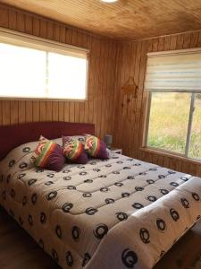 a bedroom with a bed with pillows and a window at Cabañas Nuestro Sueño in Aucho