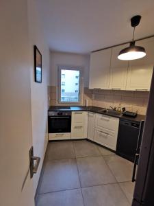 uma cozinha com armários brancos e uma máquina de lavar louça preta em Appartement Noisiel 77 (proche Disneyland & Paris) em Noisiel