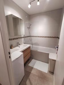 Baño blanco con bañera, lavabo y espejo en Appartement Noisiel 77 (proche Disneyland & Paris), en Noisiel