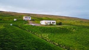 een huis bovenop een groene heuvel met een huis bij Óspaksstaðir- New Renovated Farm in Hrútafjörður in Staður