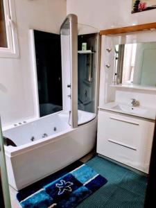 y baño con bañera y lavamanos. en La P'tite récré, 3 couchages, sauna, balnéo en Amiens