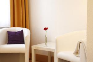einen weißen Stuhl und eine Vase mit einer Blume auf dem Tisch in der Unterkunft Stadt-gut-Hotel Rheinischer Hof in Essen + 33 Fotos