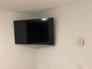 TV de pantalla plana colgada en la pared en Studio neuf meublé et équipé près d’autoroute., en Giez