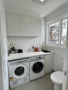 una cucina bianca con lavatrice e lavandino di Pet friendly, Family home close to town a Cowes