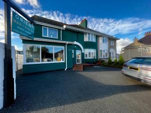 a green building with a car parked in front of it at Orient B&B in Holyhead