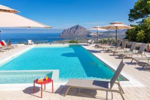 una piscina con sillas y sombrillas y el océano en Brezza D'Estate, en Valderice